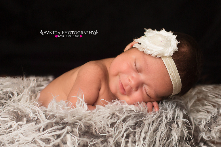 Newborn photography - baby sleeping peacefully in white headband in a sea of white flokutty rug