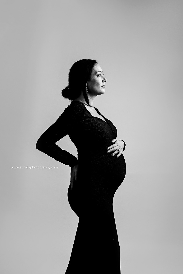 Mom-to-be strikes a majestic pose in a black and white maternity photograph