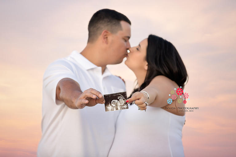 Blissful in white with the evening cloud behind them. Perfect Beach Maternity Photo by Avnida Photography.