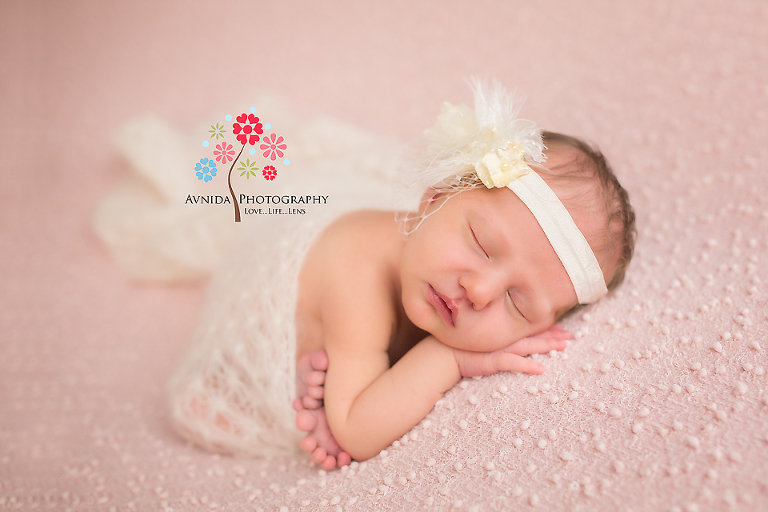 West Orange NJ newborn photographer- An angel wrapped in a white blanket with a white headband sleeps so peacefully that we just fall in love everything we see this photography