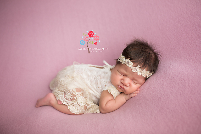 Newborn Photography Paterson NJ - There are two reasons I like this newborn photo - first the white dress looks so good on her along with the white lace headband - second, look at her expression - it's to die for