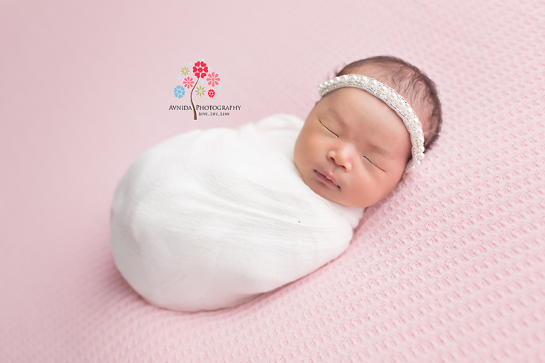 Newborn Photography Flemington NJ - The family's bundle of joy photographed in light pastel colors that complement her skin tone perfectly