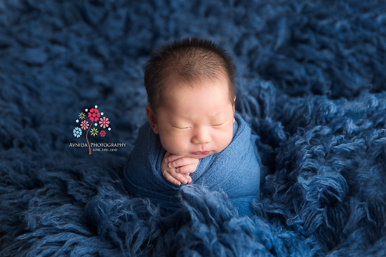 Newborn Photography Franklin Lakes NJ - The little yogi meditates in his deep thoughts, his arms crossed in a prayer while the sea of blue surrounds him