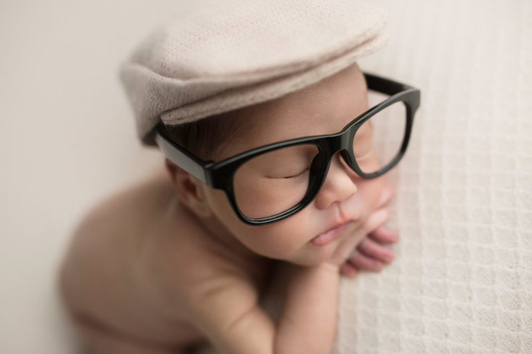 Newborn Photography Westfield NJ session by Avnida Photography. Suave and stylish, with the cap and the glasses, this charmer sleeps after a long day.