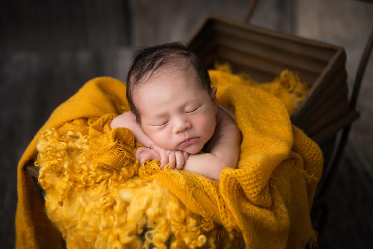 Newborn Photography Westfield NJ session by Avnida Photography. The perfect contrast of colors. The yellow blanket with the brown stroller.